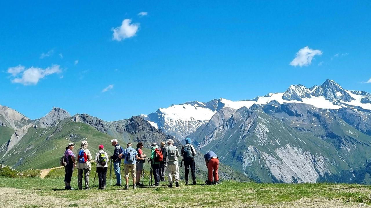 Eine Gruppe Wandertouristen steht vor dem Massiv des Großglockners im Nationalpark Hohe Tauern.