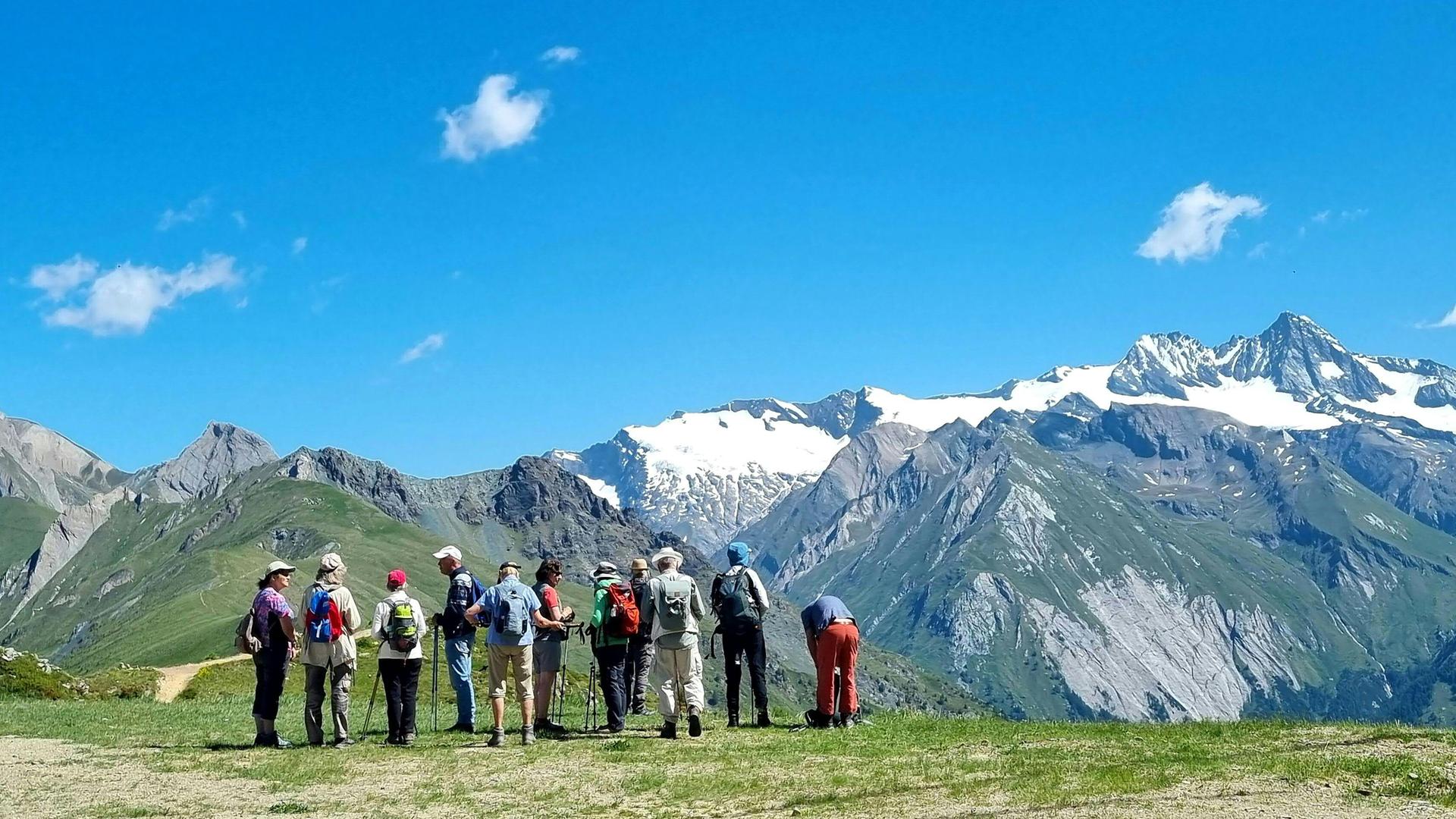Eine Gruppe Wandertouristen steht vor dem Massiv des Großglockners im Nationalpark Hohe Tauern.