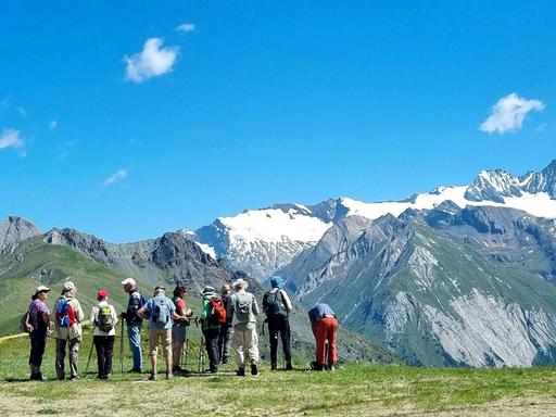Eine Gruppe Wandertouristen steht vor dem Massiv des Großglockners im Nationalpark Hohe Tauern.
