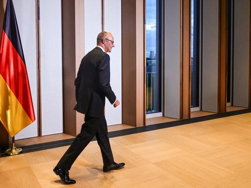 Der deutsche Bundeskanzler Friedrich Merz trifft am 10. September 2026 zu einem Galadinner in der offiziellen Residenz des Bundespräsidenten am Spreebogen in Berlin ein. Er geht durch einen Flur, neben ihm die deutsche Flagge.
