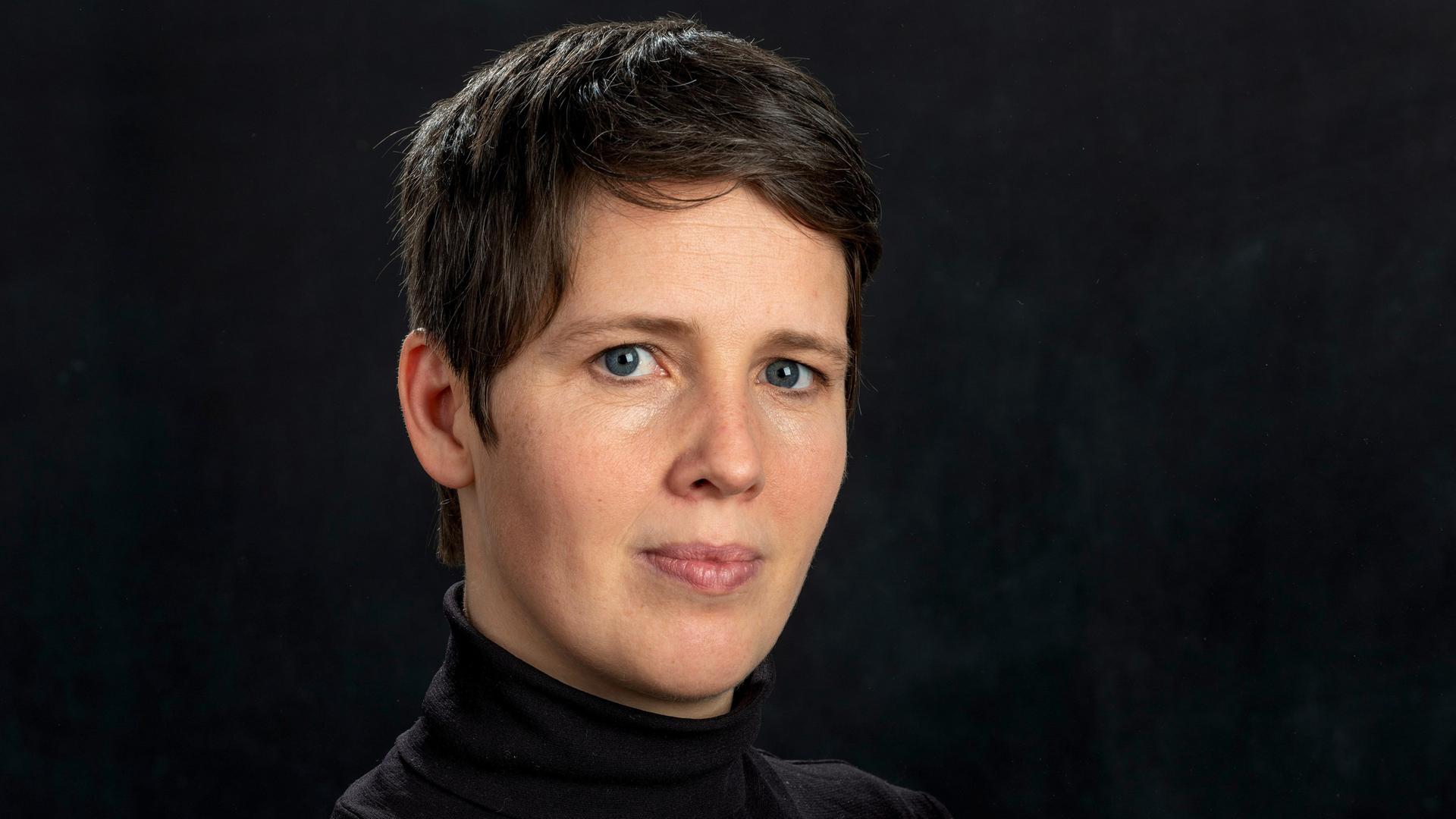 Porträt der Physikerin Viola Priesemann vor dunklem Hintergrund