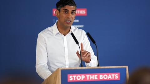 Rishi Sunak spricht während einer Pressekonferenz. An seinem Podium ist der Slogan "Stop the Boats" angebracht.