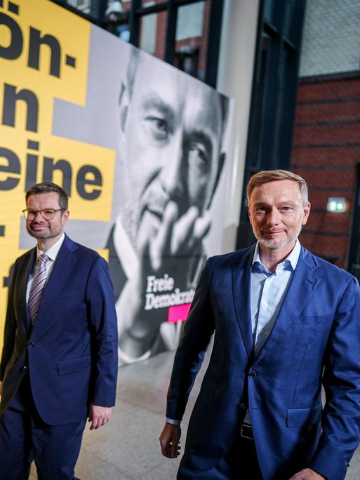 Christian Lindner und Marco Buschmann gehen an einem FDP-Wahlplakat entlang.