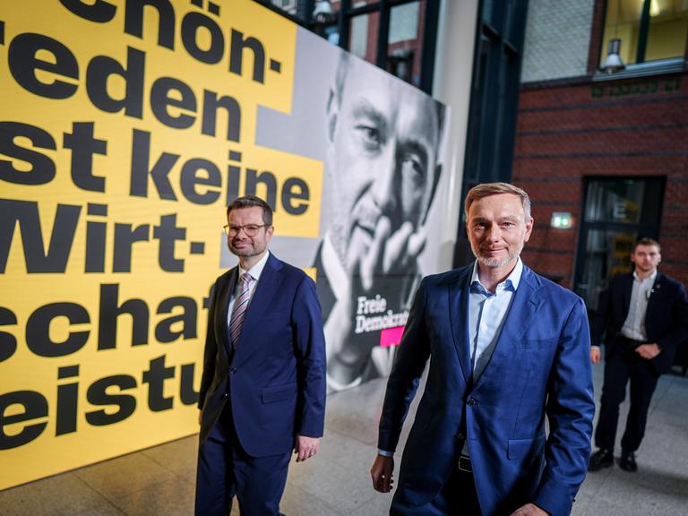 Christian Lindner und Marco Buschmann gehen an einem FDP-Wahlplakat entlang.