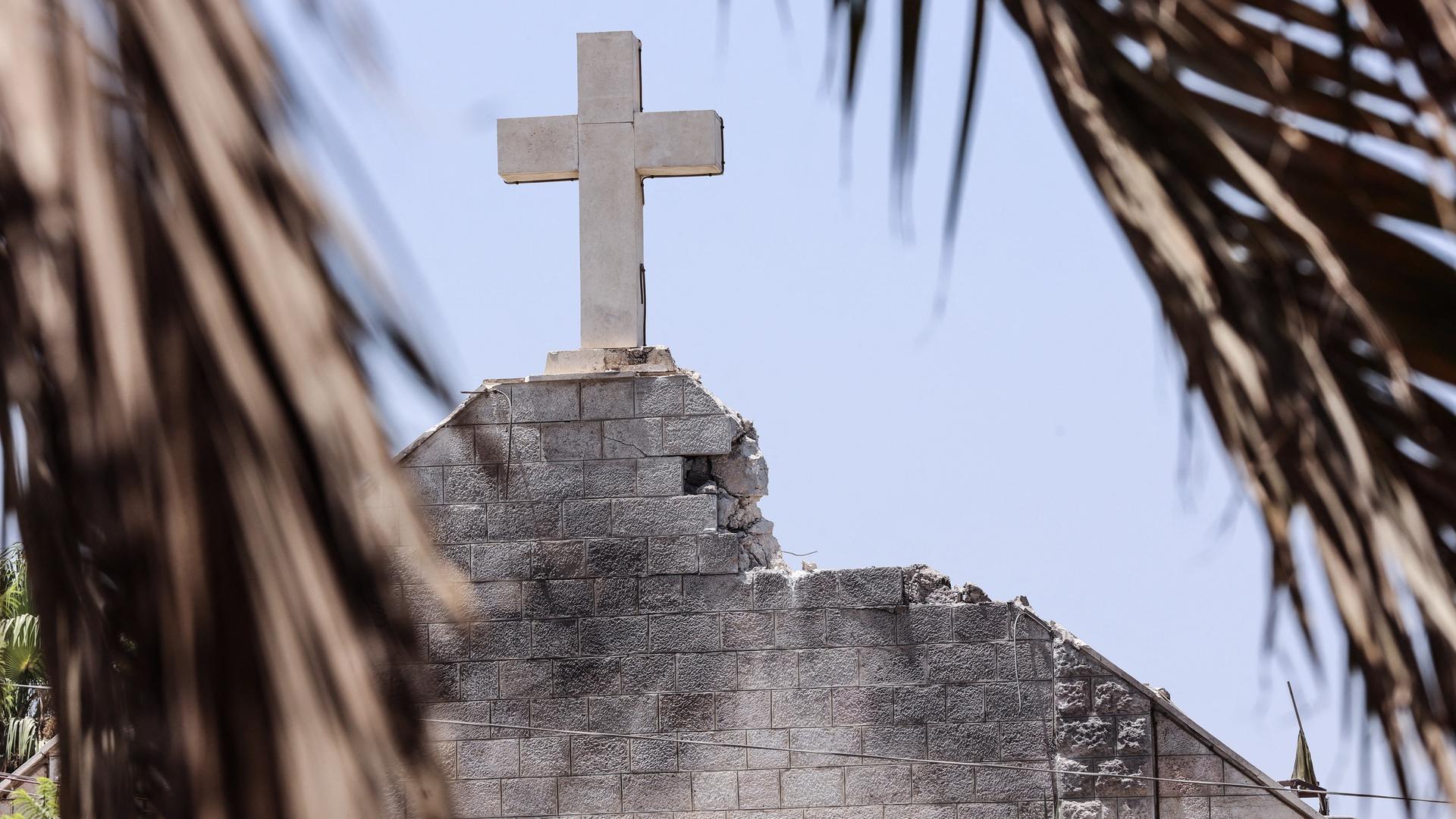 Man sieht die Spitze mit dem Kreuz der Kirche, neben dem Kreuz sind Steine herausgebrochen. Man sieht die Spitze mit dem Kreuz der Kirche, neben dem Kreuz sind Steine herausgebrochen.