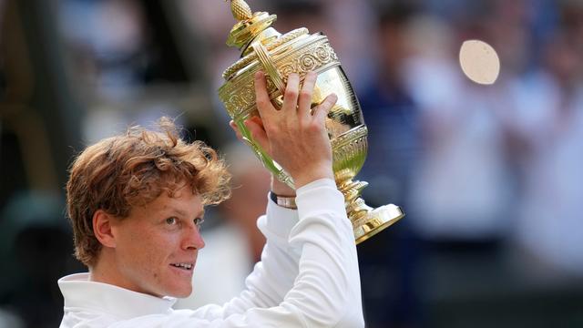 Das Bild zeigt den italienischen Tennis-Spieler Jannik Sinner. Er hält in Wimbledon den Siegerpokal in die Luft.