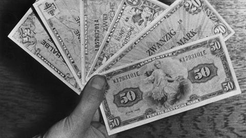 Eine Hand hält sechs Deutsche-Mark-Banknoten Eine Hand hält sechs Deutsche-Mark-Banknoten