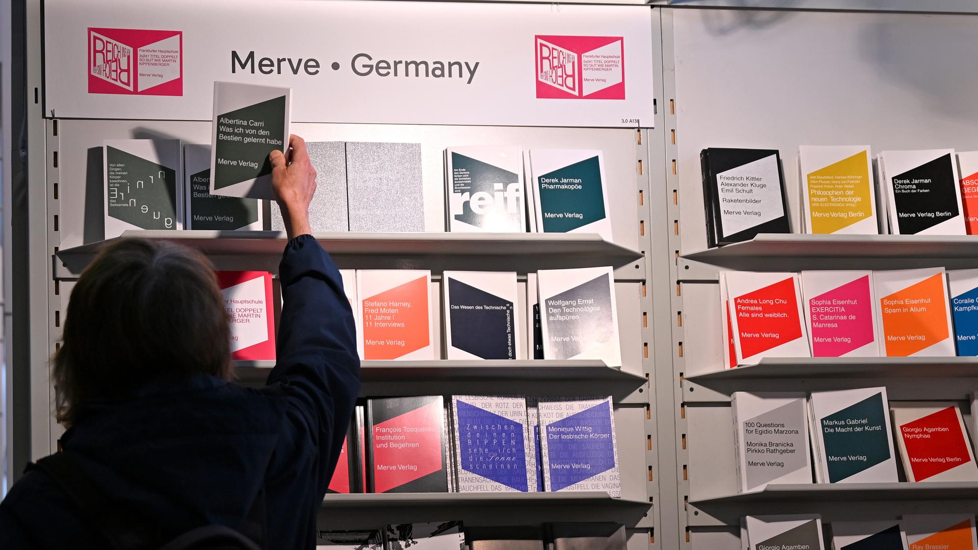Eine Frau greift nach einem Buch, das in einem Regal des Merve Verlags auf der Frankfurter Buchmesse steht. Eine Frau greift nach einem Buch, das in einem Regal des Merve Verlags auf der Frankfurter Buchmesse steht.