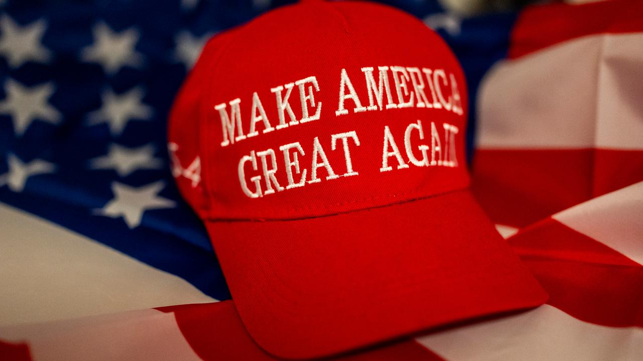 Eine rote "Make America Great Again"-Kappe liegt auf einer US-Flagge als Symbol politischer Unterstützung für Donald Trump in den Vereinigten Staaten. 