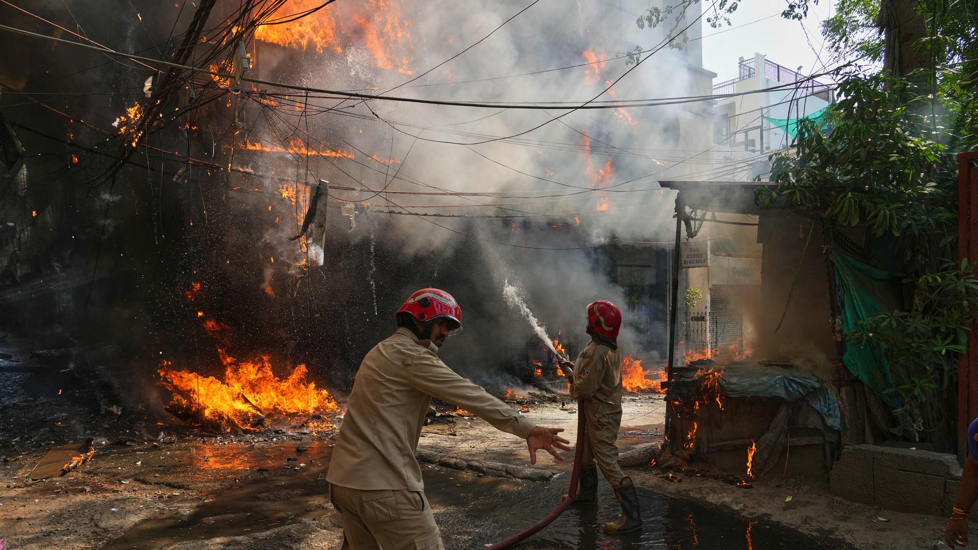 Indien, Neu Delhi: Feuerwehrleute löschen ein Feuer in einem Gebäude.