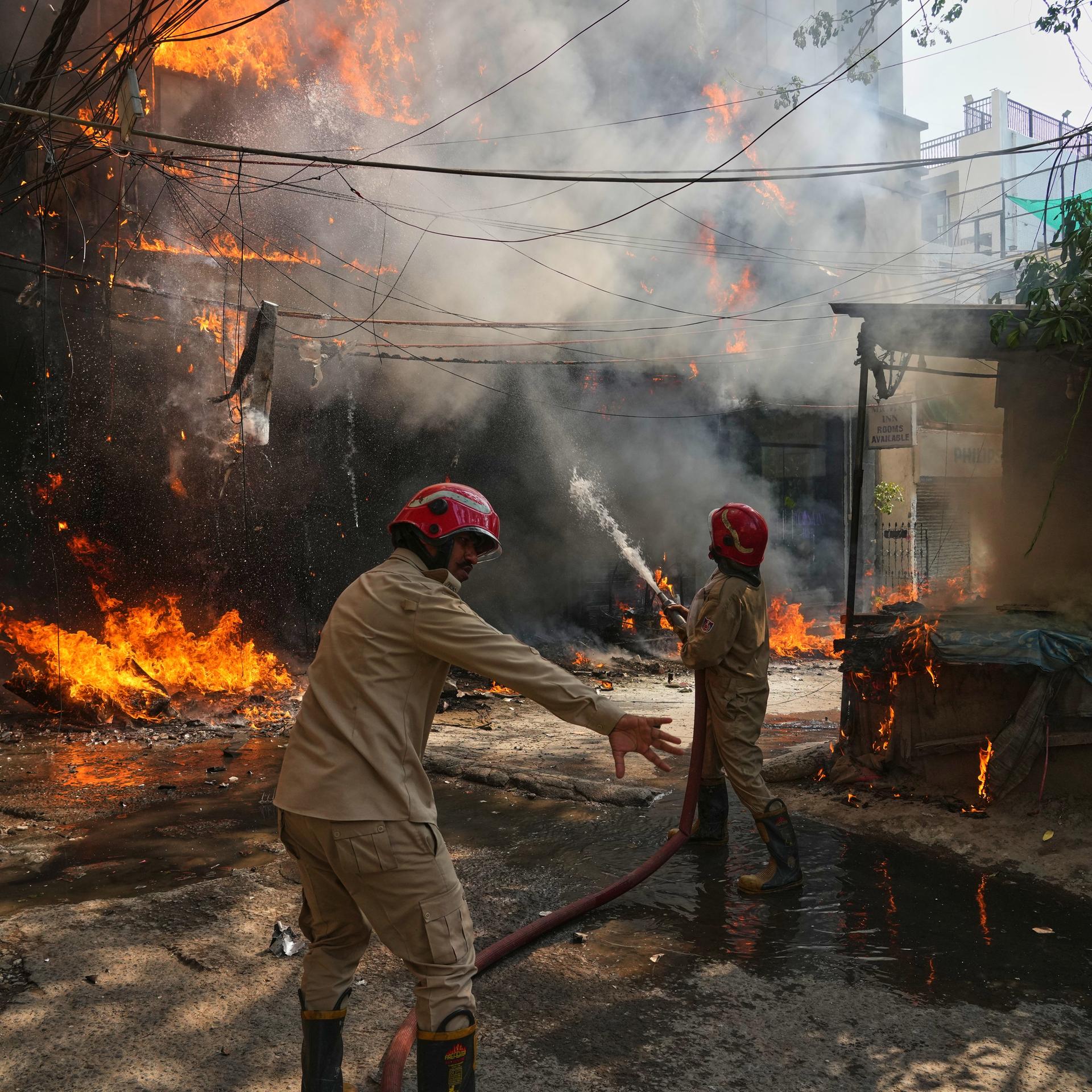 Indien, Neu Delhi: Feuerwehrleute löschen ein Feuer in einem Gebäude.