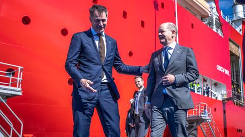 Der belgische Premierminister Alexander De Croo begrüßt Bundeskanzler Olaf Scholz zu Beginn des Nordsee-Gipfels in Ostende, im Hintergrund ist ein rotes Schiff zu sehen.