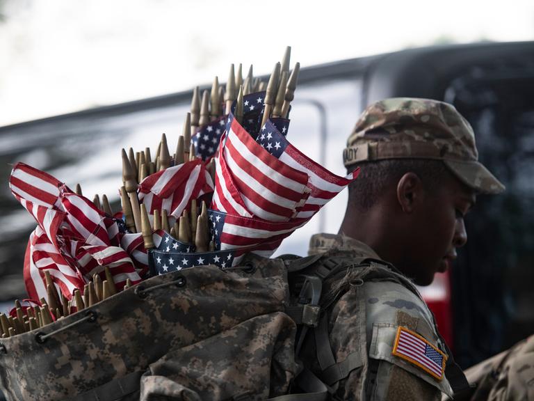 Memorial Day in Arlington: Ein US-Soldat trägt Flaggen in einem Rucksack. Mit diesen sollen gefallene Soldaten geehrt werden.