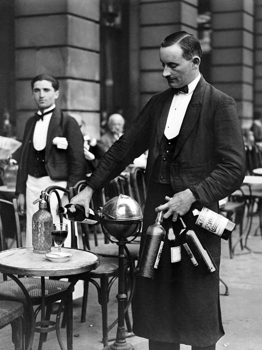 Ein Kellner, der im Jahr 1928 in einem Pariser Bistro Wein einschenkt.