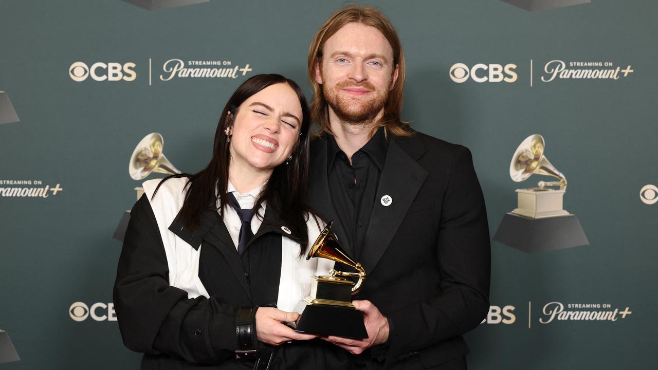 Billie Eilish und ihr Bruder Finneas posieren mit ihrem Grammy vor einer Fotowand. 