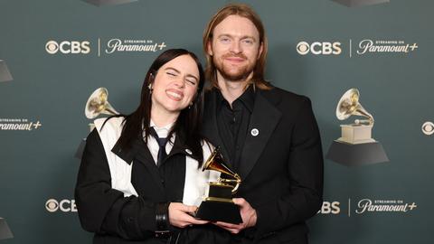 Billie Eilish und ihr Bruder Finneas posieren mit ihrem Grammy vor einer Fotowand. Billie Eilish und ihr Bruder Finneas posieren mit ihrem Grammy vor einer Fotowand.