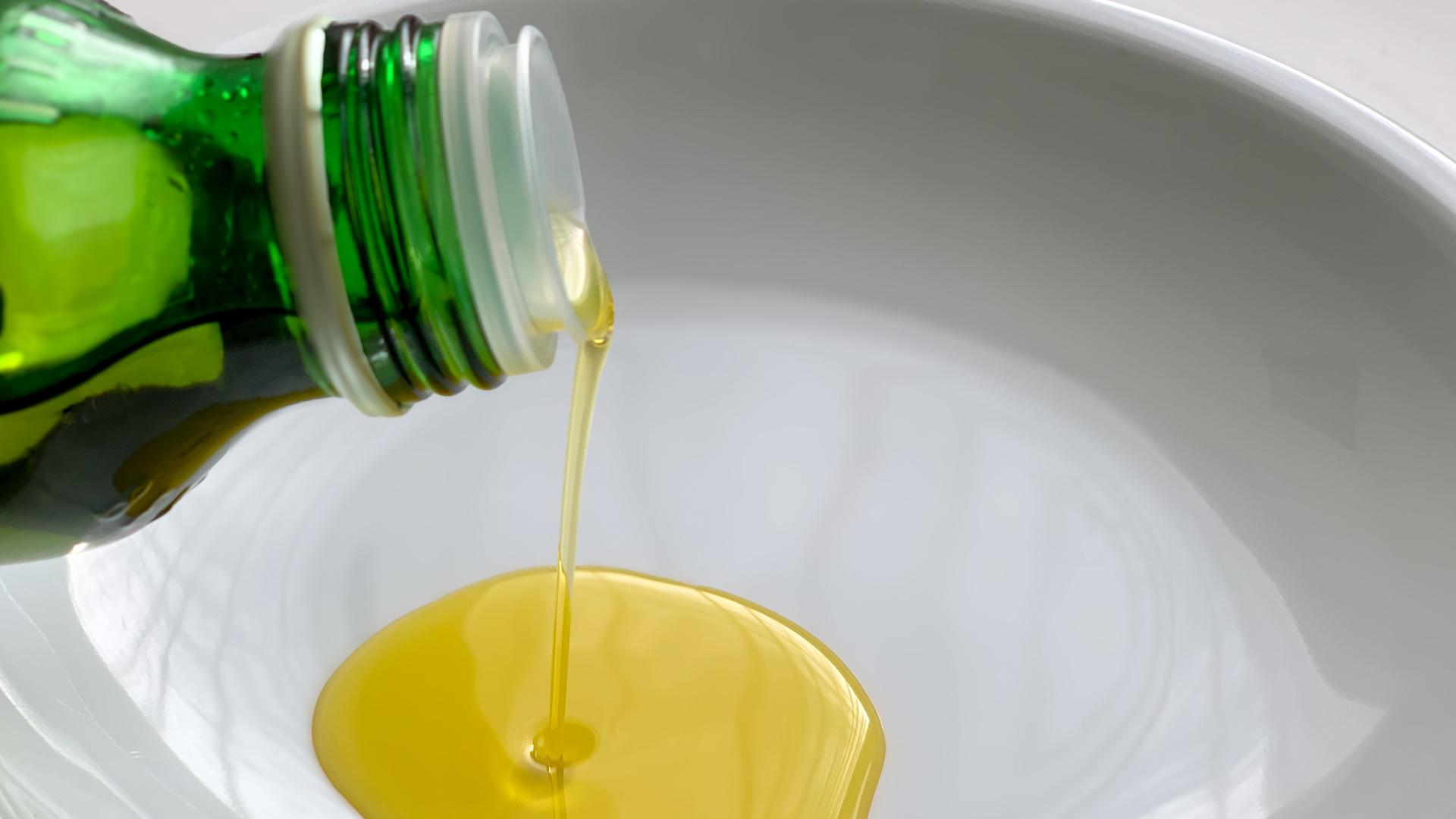 Olivenöl wird aus einer Flasche in eine Schale gegossen