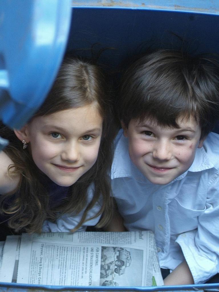 Kinder spielen in Papiermüll-Tonnen