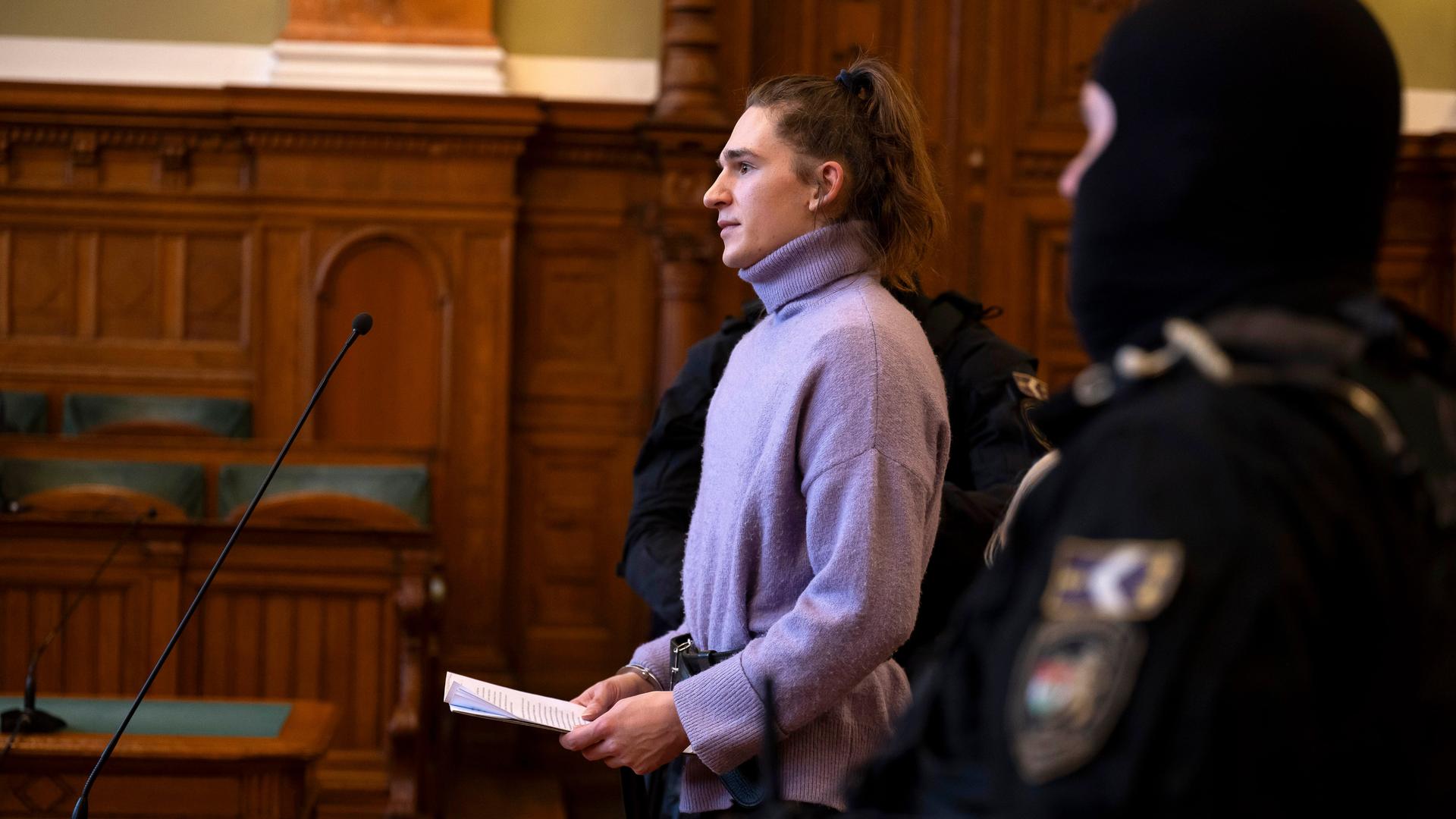 Maja T. trägt einen lila Rollkragenpullover und Handschellen im Gerichtsaal Maja T. trägt einen lila Rollkragenpullover und Handschellen im Gerichtsaal