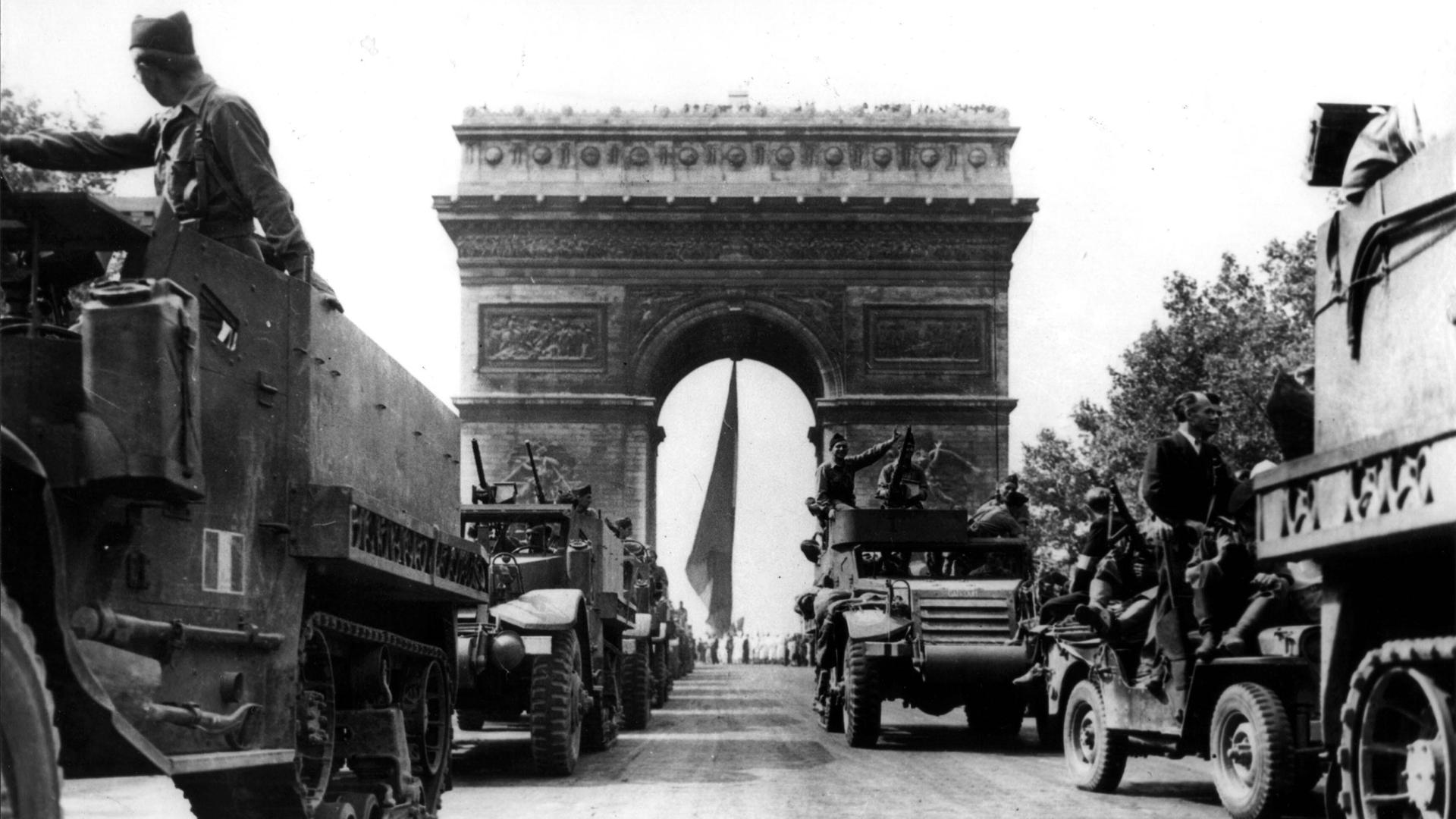 Schwarz-Weiß-Foto gepanzerter Fahrzeuge der zweiten französischen Division vor dem Triumphbogen in Paris.