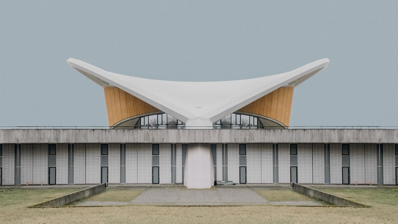Die Fotografie der Künstlerin Sarah Eick zeigt das Haus der Kulturen der Welt im Berliner Tiergarten als Einzelgebäude vor einem blassblauen Hintergrund. Die Fotografie der Künstlerin Sarah Eick zeigt das Haus der Kulturen der Welt im Berliner Tiergarten als Einzelgebäude vor einem blassblauen Hintergrund.
