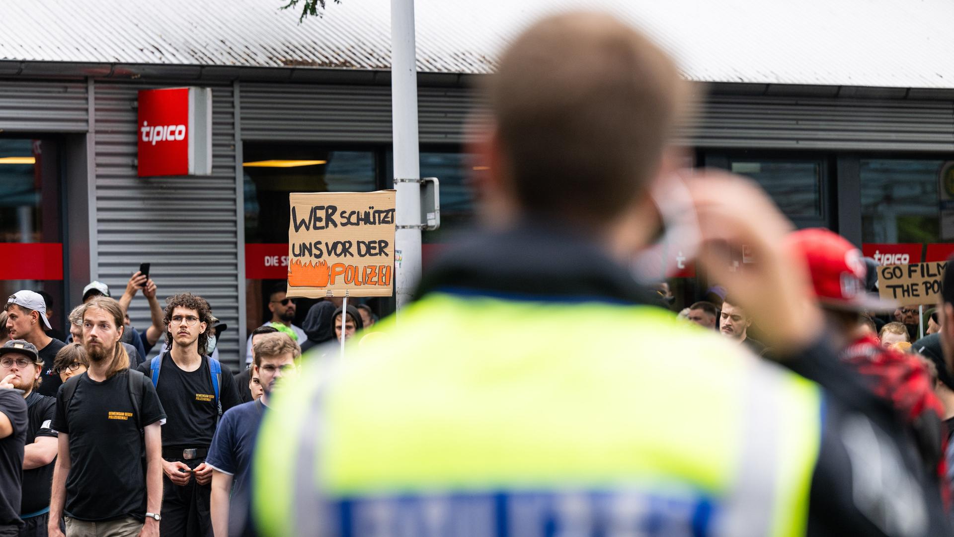 Ein Demonstrations-Teilnehmer im nordrhein-westfälischen Herford trägt ein Plakat mit der Aufschrift: "Wer schützt uns vor der Polizei".