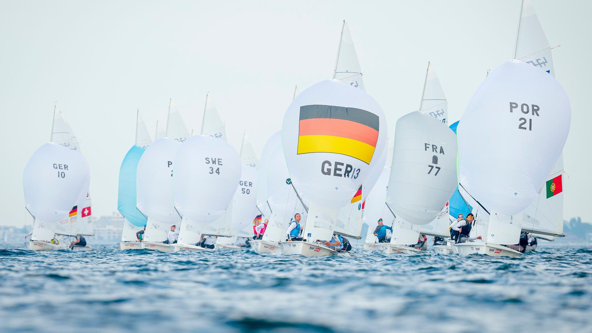 Mehrere Segelboote - unter anderem eines mit deutscher Flagge - bei einer Regatta bei der Kieler Woche 2022.