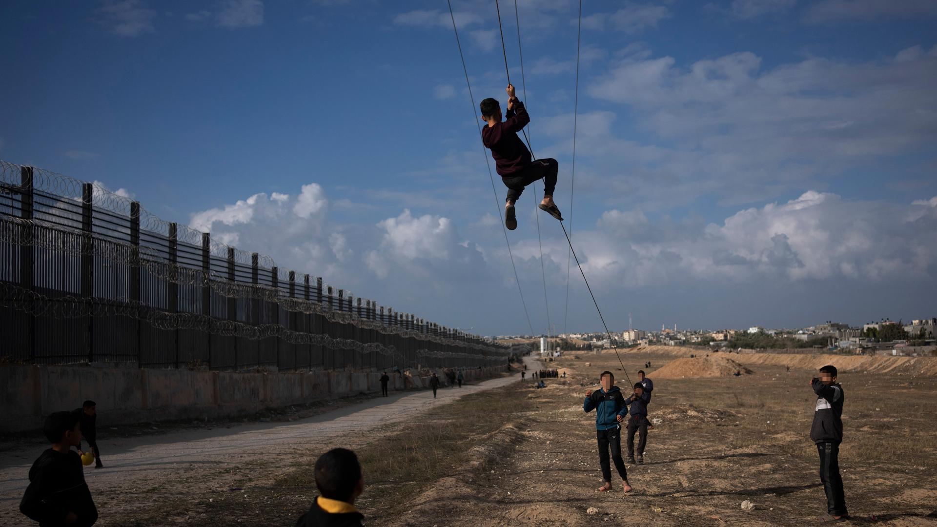 An den Grenzanlagen zwischen Gaza und Ägypten spielen Kinder. Nach hinten geht der Blick den "Philadelphi Korridor" entlang. Der Himmel ist blau.