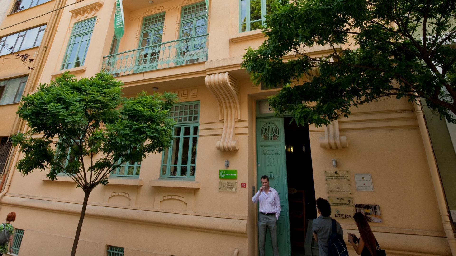 Das sepiafarbene Gebäude des Goethe-Instituts in Istanbul, davor steht ein Mann und raucht. 