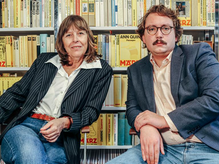 Barbara Kalender und Richard Stoiber, Verleger des März Verlags, sitzen vor einer Bücherwand. 