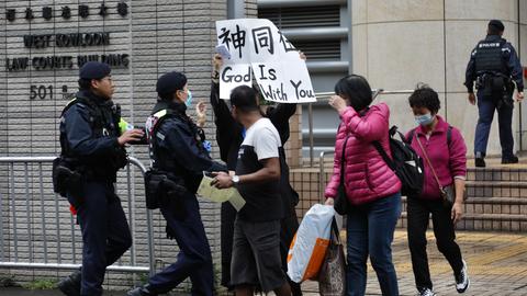 Hongkong: Ein Polizist versucht, eine Frau daran zu hindern, vor dem Gericht in West Kowloon ein Transparent mit der Aufschrift "Gott ist mit dir" in englischer und chinesischer Sprache zu zeigen. 