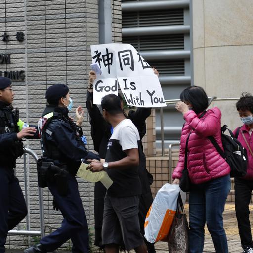 Hongkong: Ein Polizist versucht, eine Frau daran zu hindern, vor dem Gericht in West Kowloon ein Transparent mit der Aufschrift "Gott ist mit dir" in englischer und chinesischer Sprache zu zeigen. 