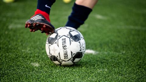 Ein Kickschuh streift während eines Dirbblings über eine Fußball