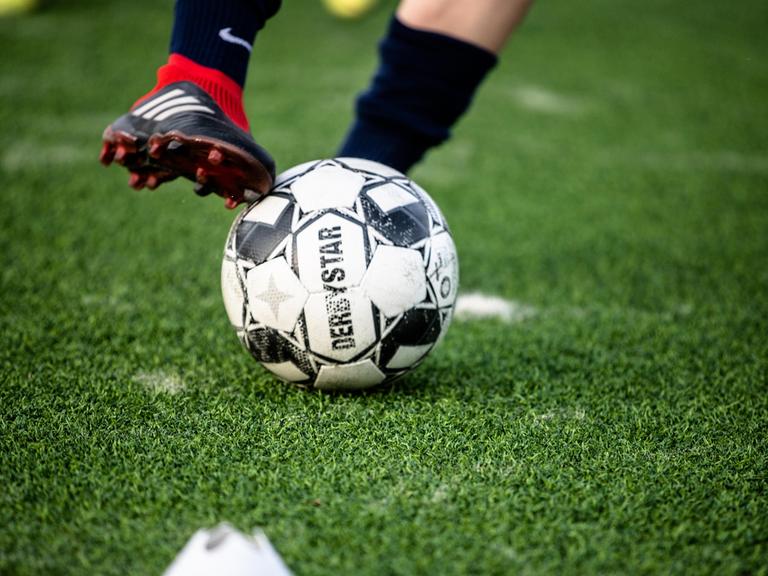 Ein Kickschuh streift während eines Dirbblings über eine Fußball