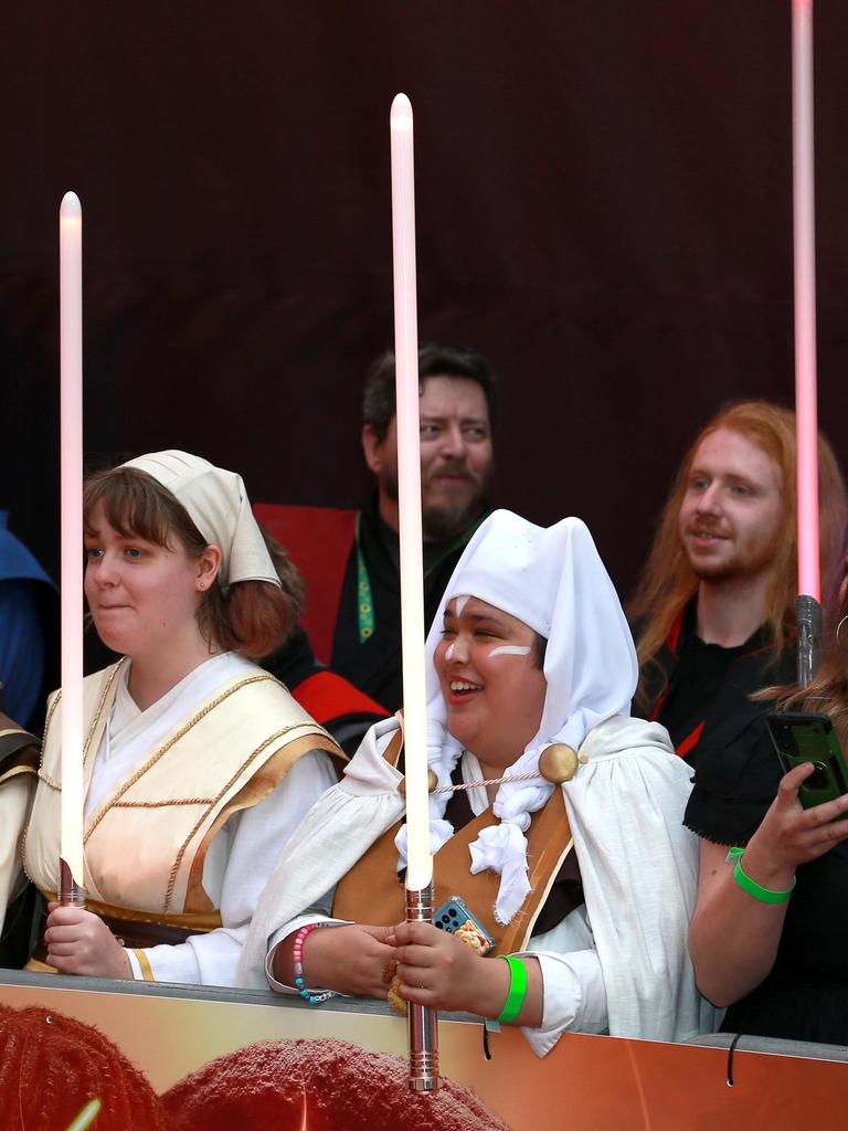 Mehrere weibliche Star-Wars-Fans halten auf der Premiere von Star Wars: Acolyte" Lichtschwerter in die Höhe.