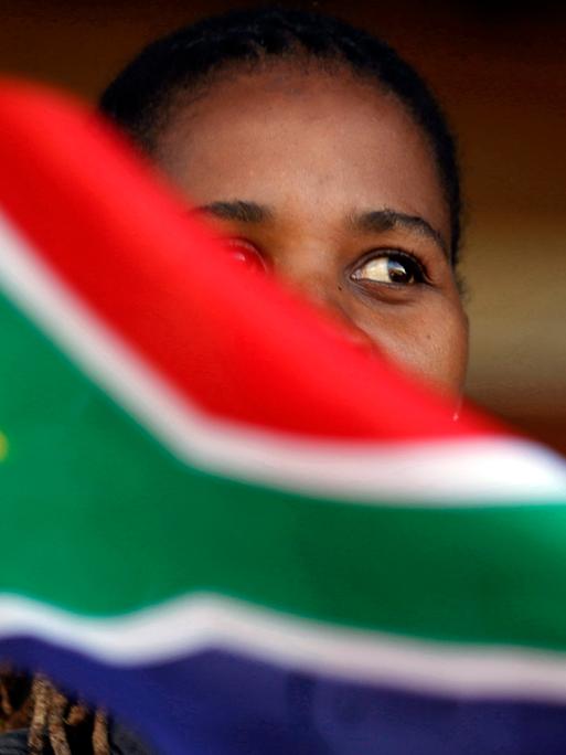 Eine schwarze Frau schwenkt bei dem Feierlichkeiten zum Freedom Day am 27. April 2019 eine Südafrikaflagge, die Teile ihres Gesichts verdeckt.
