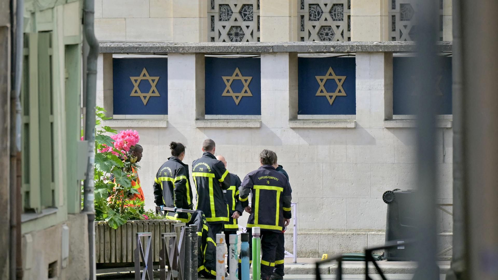 Mitglieder der Feuerwehr an der Synagoge in Rouen, wo die Polizei zuvor einen Angreifer getötet hatte. (Photo by LOU BENOIST / AFP) Mitglieder der Feuerwehr an der Synagoge in Rouen, wo die Polizei zuvor einen Angreifer getötet hatte. (Photo by LOU BENOIST / AFP)