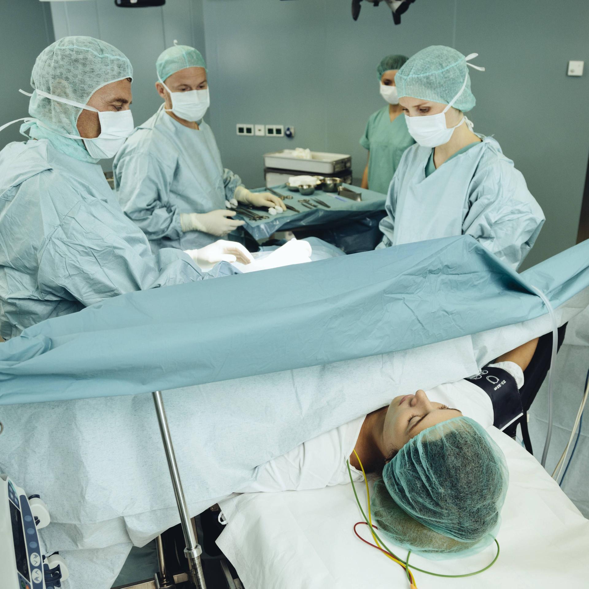 Ein Team operiert eine Frau auf einem Operationstisch.
