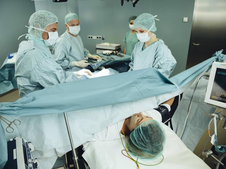 Ein Team operiert eine Frau auf einem Operationstisch.