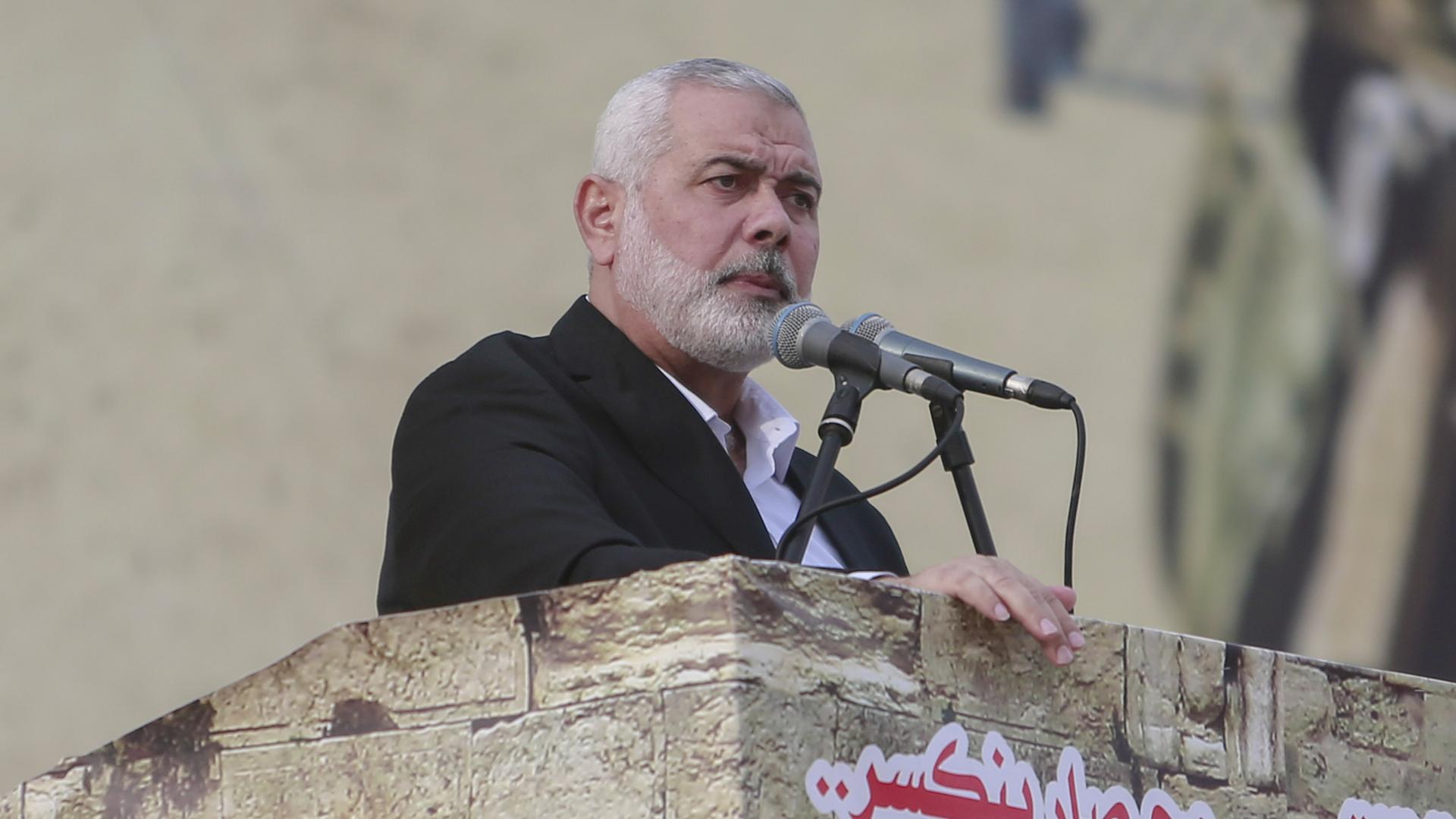 Hamas-Chef Ismail Hanija steht mit ernstem Blick an einem Rednerpult aus Stein vor Mikrofonen.