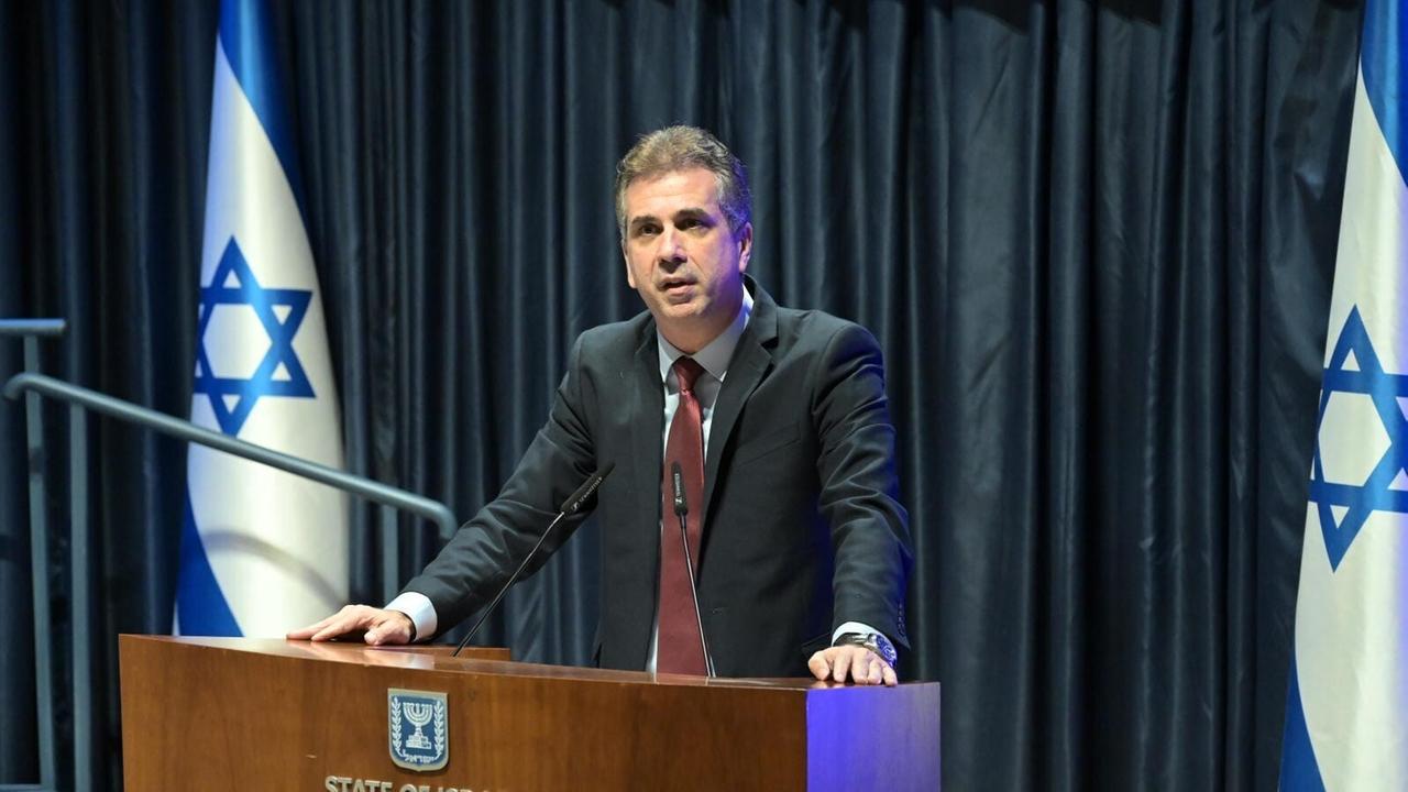 Der israelische Außenminister Eli Cohen steht an einem Rednerpult, links und rechts von ihm sind die Landesflaggen aufgestellt.
