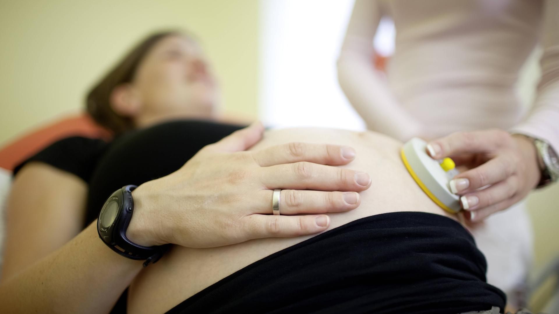 Der Bauch einer schwangeren Frau wird untersucht