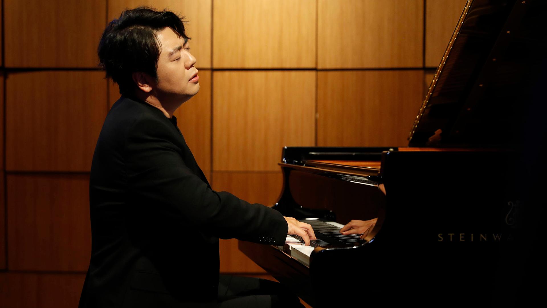 Der chinesischer Pianist Lang Lang am Klavier sitzend und mit geschlossenen Augen spielend Der chinesischer Pianist Lang Lang am Klavier sitzend und mit geschlossenen Augen spielend