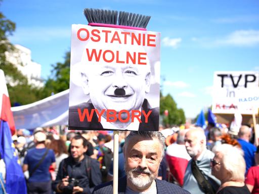 Ein Mann hält ein Plakat in die Höhe, auf dem der Chef der rechtsnationale Regierungspartei PiS, Jaroslaw Kaczynski, zu sehen ist