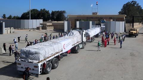Mehrere Lastwagen beladen mit weißen Paketen am Grenzübergang Rafah.