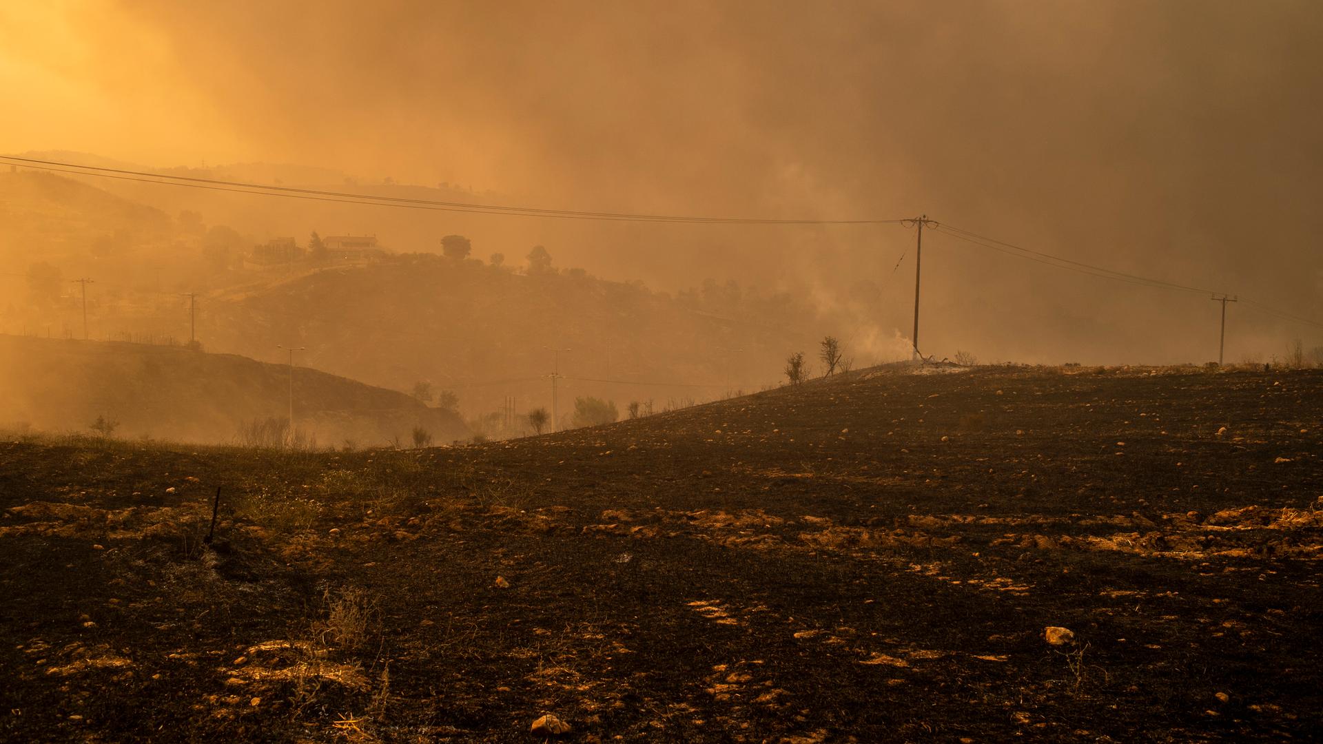 Rauch steigt von verbranntem Gelände in einem Waldgebiet nördlich von Athen auf