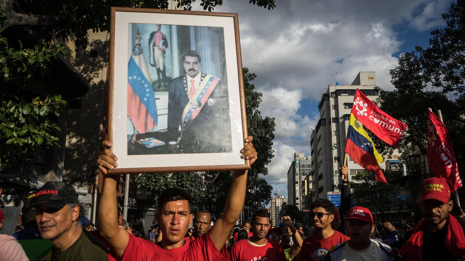 Unterstützer von Venezuelas bisherigem Staatspräsident Nicolás Maduro hält bei einer Demonstration in Caracas ein gerahmtes Portrait von Maduro in die Höhe.