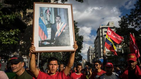 Unterstützer von Venezuelas bisherigem Staatspräsident Nicolás Maduro hält bei einer Demonstration in Caracas ein gerahmtes Portrait von Maduro in die Höhe.
