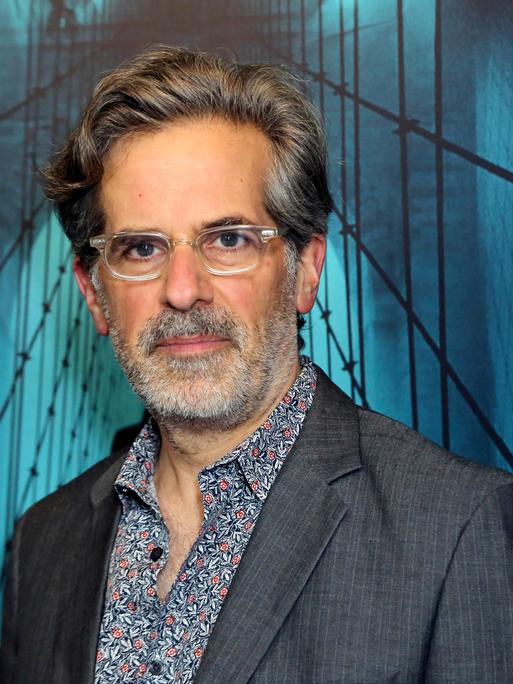 Der US-Schriftsteller Jonathan Lethem mit Bart und Brille vor blauem Hintergrund. 