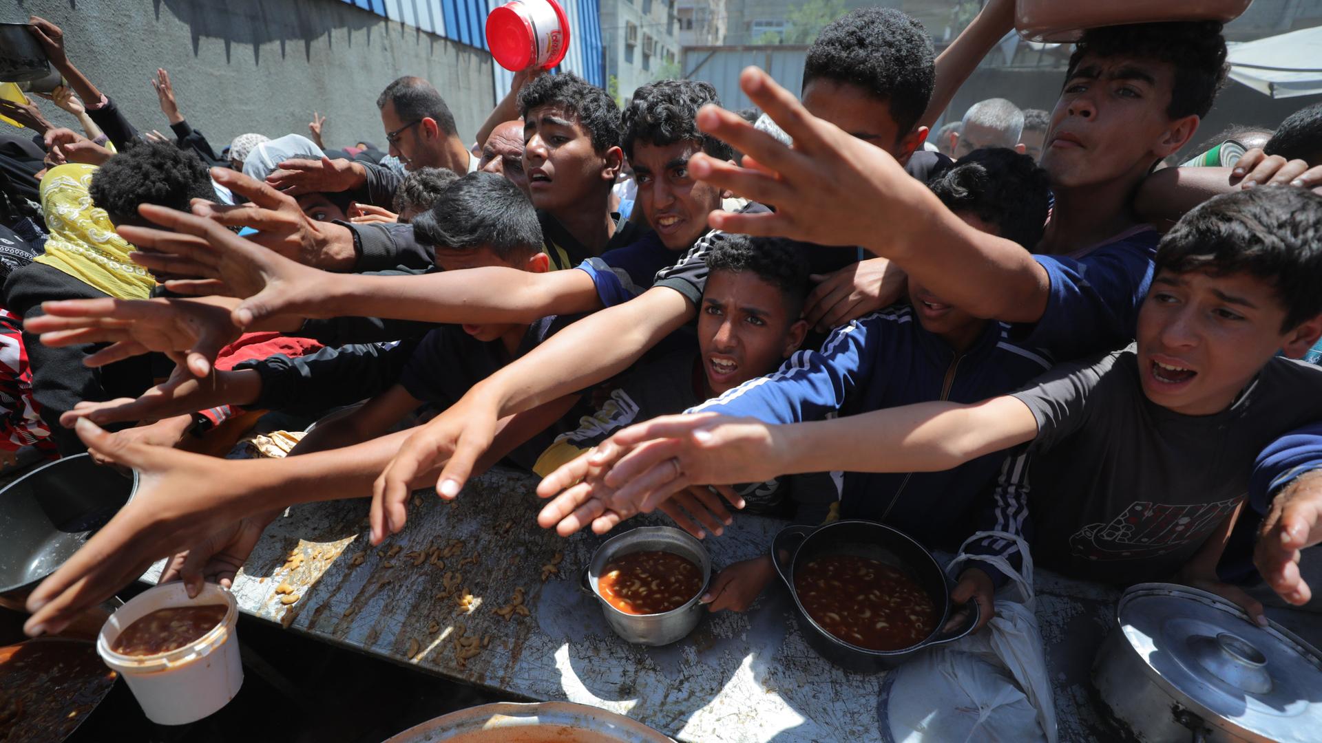 Palästinenser, hauptsächlich Kinder, warten in langen Schlangen mit leeren Töpfen in den Händen auf eine warme Mahlzeit, die im Lager Nuseirat, Gaza, verteilt wird, am 26. April 2025